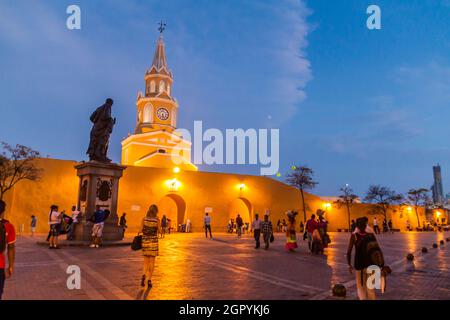 CARTAGENA DE INDIAS, COLOMBIA - AUG 27, 2015: People walk at the Plaza de los Coches in Cartagena during evening. Clock tower in the background. Stock Photo