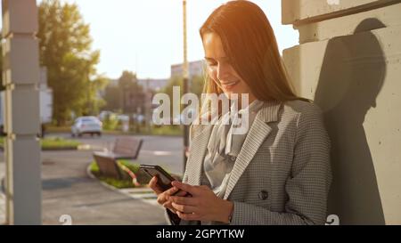 young woman in a business suit with a phone stands on the street Stock Photo