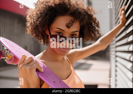 A curly-haired woman with a skateboard in hands Stock Photo
