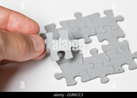 Photo of a person adding last piece of jigsaw puzzle to fit together on white background Stock Photo