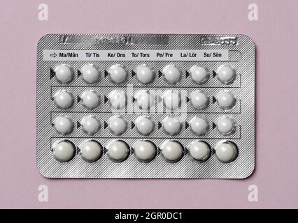 Overhead of a full chart of birth control pills on pink background Stock Photo