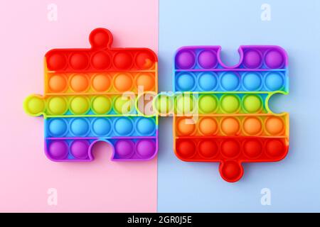 Popit toy in the form of a puzzles on a colorful background. Multicolored Pop it toy Stock Photo