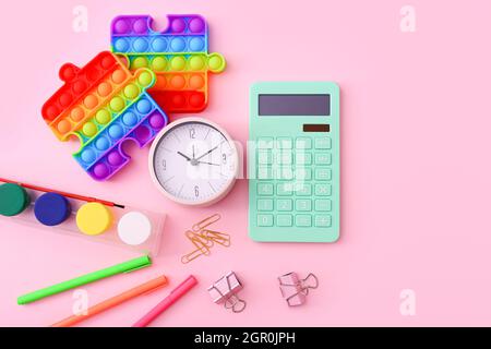Flat lay of stationery, clock and silicone toys popit on pink background Stock Photo