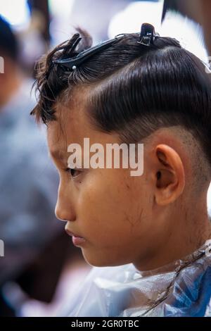 Portrait of young boy with bun hairstyle looking sideways against yellow  background Stock Photo - Alamy