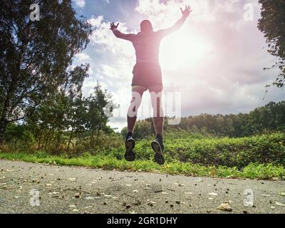 Jogging Tall Sports Man In Trees Shadows With Sun Light Behind Him While Wearing Black Yellow Shorts
