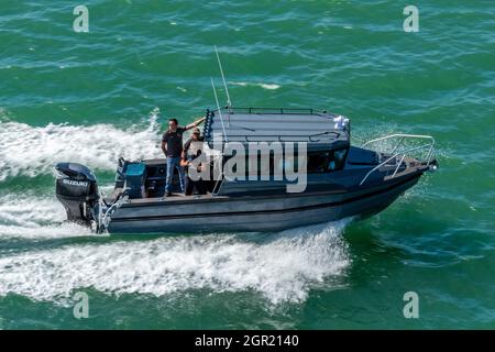 modern fast fishing boat with an outboard engine with fishermen standing on the deck. state-of-the-art fishing boat speeding through the water sea. Stock Photo