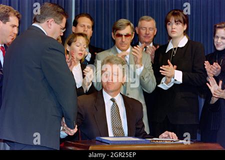 Washington, DC, USA. 12th March 1996. U.S President Bill Clinton shakes hands with Rep. Robert Menendez, (D-NJ), left, following the signing of the Helms-Burton bill to tighten the Cuban embargo at the Old Executive Office Building of the White House March 12, 1996 in Washington, D.C. Surrounding the president are family members of Brothers to the Rescue pilots who were killed when their planes were shot down by Cuban fighter jets. Stock Photo