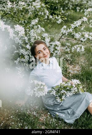 Beautiful Pretty Young Woman Walks Enjoying The Aroma Of Blooming Apple Flowers In A Spring Park