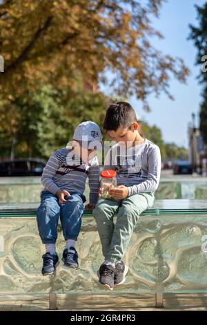 POZNAN, POLAND - Sep 05, 2021: Two young Polish boys sitting on a glass barrier and watching bugs in a jar Stock Photo