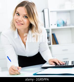 Careful girl writes something on sheet of paper in office Stock Photo