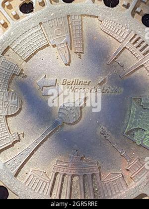 Berlin Germany - August 27 2017; Ornate heavy steel waste-water manhole cover with imaging of Berlin TV tower and buildings in city street Stock Photo