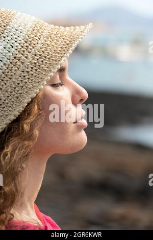 Profile portrait close up of a young hispanic woman with closed eyes breathing deep fresh air and wearing a hat Stock Photo