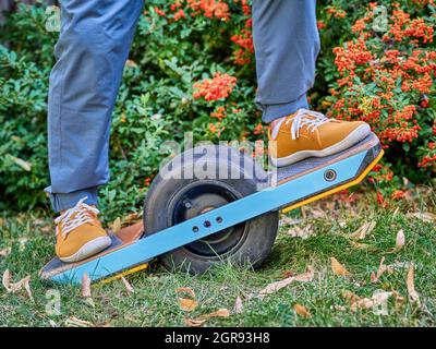 riding one-wheeled electric skateboard in a backyard or park Stock Photo