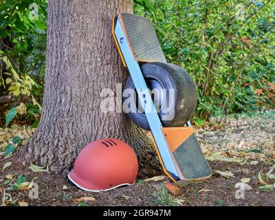 one-wheeled electric skateboard with a helmet in a park in fall scenery Stock Photo