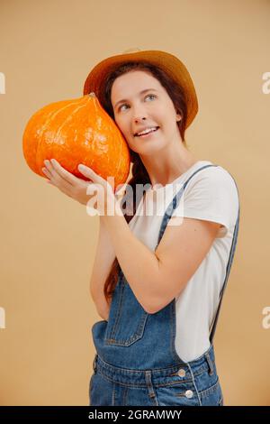 Happy farmer woman presses a large ripe pumpkin to her face. Stock Photo