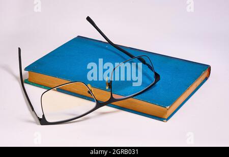 Glasses was taken off and put on a blue book. White background Stock Photo
