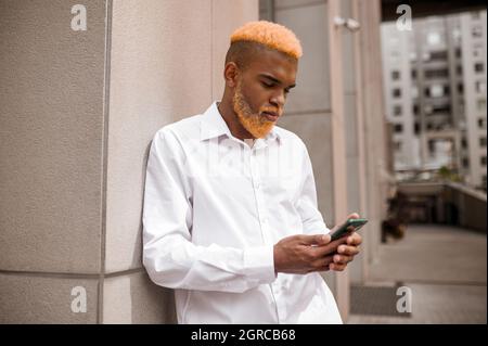 A picture of a tall dark-skinned man in white clothes on a urban background Stock Photo