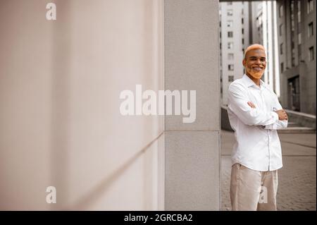 A picture of a tall dark-skinned man in white clothes on a urban background Stock Photo