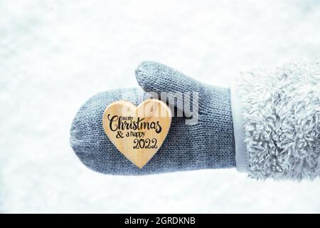 Sto Christmas 2022 Heart With English Calligraphy Merry Christmas And A Happy 2021. Hand In A  Glove With Fleece And Snow Stock Photo - Alamy