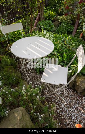 Empty bistro coffee table with chairs in green garden Stock Photo