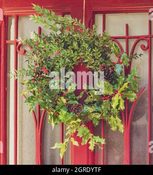 Christmas holly wreath on a vintage red door Stock Photo