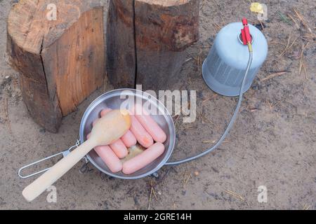 Camping food making. Tourist foods in outdoor activities. Sausages in bowler in the forest. Stock Photo