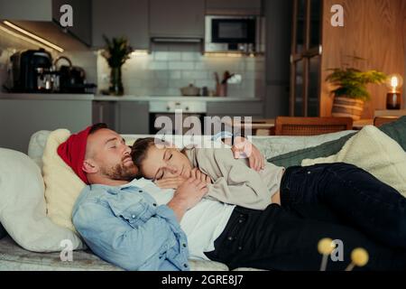 Caucasian couple lying on sofa cuddling bonding together Stock Photo