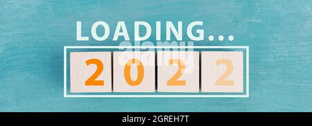 2022 is standing in orange colored letters on wooden cubes, the word loading is standing above Stock Photo