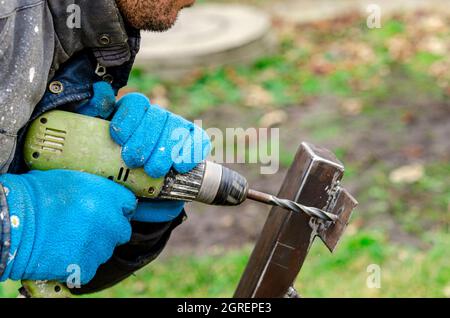 Drill screwdriver workflow creation of metal parts. male metal worker using drillpress. Toned image. from the side view Stock Photo