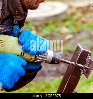 Drill screwdriver workflow creation of metal parts. male metal worker using drillpress. Toned image. from the side view Stock Photo
