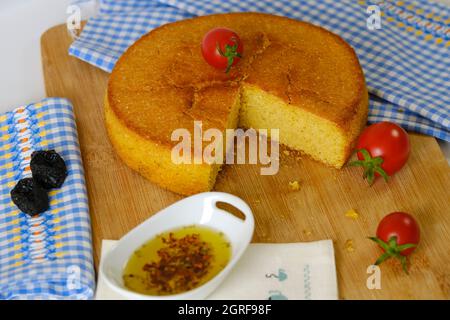 Cornbread cherry tomatoes and olive oil on wooden cutting board and blue white colored plaid Stock Photo