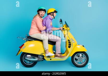 Profile side view of attractive cheerful amazed couple riding bike having fun isolated over bright blue color background Stock Photo