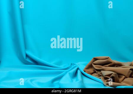 Crumpled fabric in pale blue and beige with elegant pleats for the background. Selective focus. Stock Photo