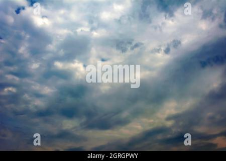 Golden clouds and dark storm clouds against a blue sky background Stock Photo