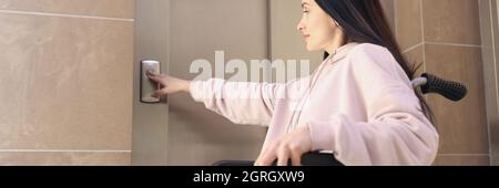 Disabled woman in wheelchair presses call button Stock Photo