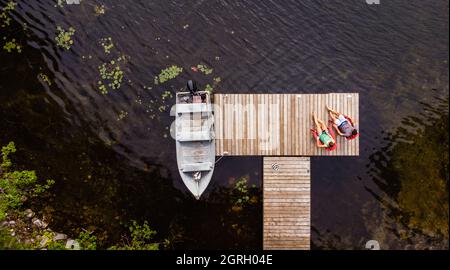 Overhead aerial image of couple sitting on a dock together. Stock Photo