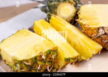 Fresh juicy yellow pineapple fruit slices on light wooden board background. Stock Photo