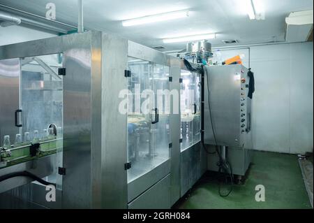 Beverage bottling room with automatic machinery and control panel in production line at beverage processing factory Stock Photo