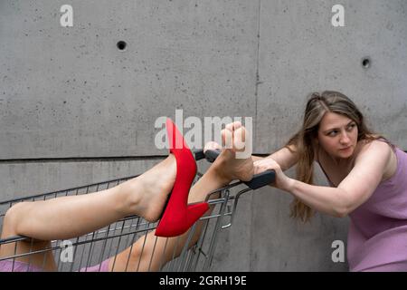 Young woman pushing shoping cart with other woman in it Stock Photo