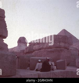 Große Sphinx von Gizeh, als Wächter der Pyramiden, mit der Pyramide des Cheops im Hintergrund, Ägypten 1955. Great Sphinx of Giza, as the pyramid's guardian, with pyramid of Khufu in the background, Egypt 1955. Stock Photo