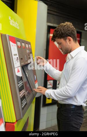 Side view of male entrepreneur inserting credit card into machine while buying ticket on subway station Stock Photo