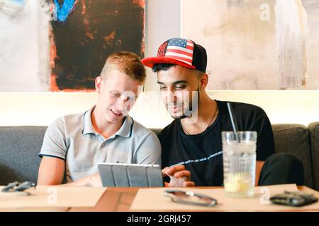 Male friends in cafe talk discuss with technology phone tablet Stock Photo
