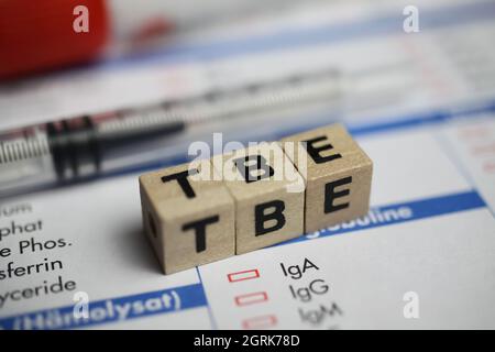 Viersen, Germany - June 1. 2021: Closeup of word TBE (tick borne encephalitis) on laboratory requisition slip with syringe and vial Stock Photo