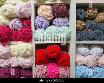 Colorful yarns or balls of different types of wool for knitting on shelves in the haberdashery shop. Knitwork handcraft concept Stock Photo