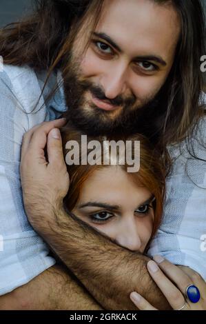 Portrait of a young couple embraced where the bearded man holds the head of the young red-haired woman in his hands Stock Photo