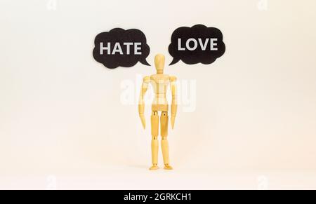 Love or hate symbol. Wooden model of businessman human. Black paper with words 'love hate'. Beautiful white background, copy space. Business, psycholo Stock Photo