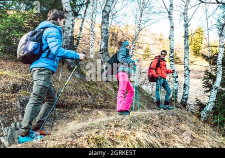 Friends group trekking in forest on french alps before sunset - Hikers with sticks walking togeether on mountain woods - Wanderlust travel concept wit Stock Photo
