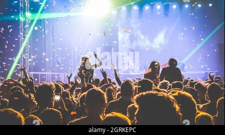 Young people dancing at night club - Hands up and multicolored confetti at nightclub after party - Nightlife concept with afterparty crowd Stock Photo