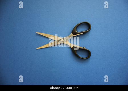 scissors on a blue background in natural light Stock Photo