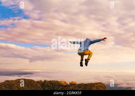 Man Jumping On Mountain Summit Peak Top Successful Winning Concept Above Clouds Stock Photo
